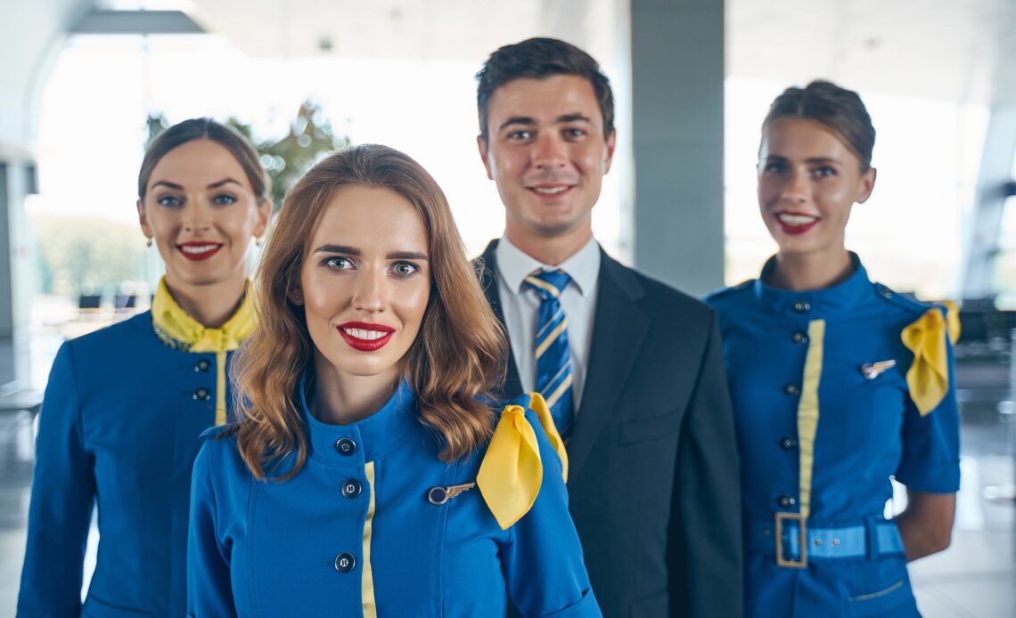 Handsome steward and female flight attendants looking forward