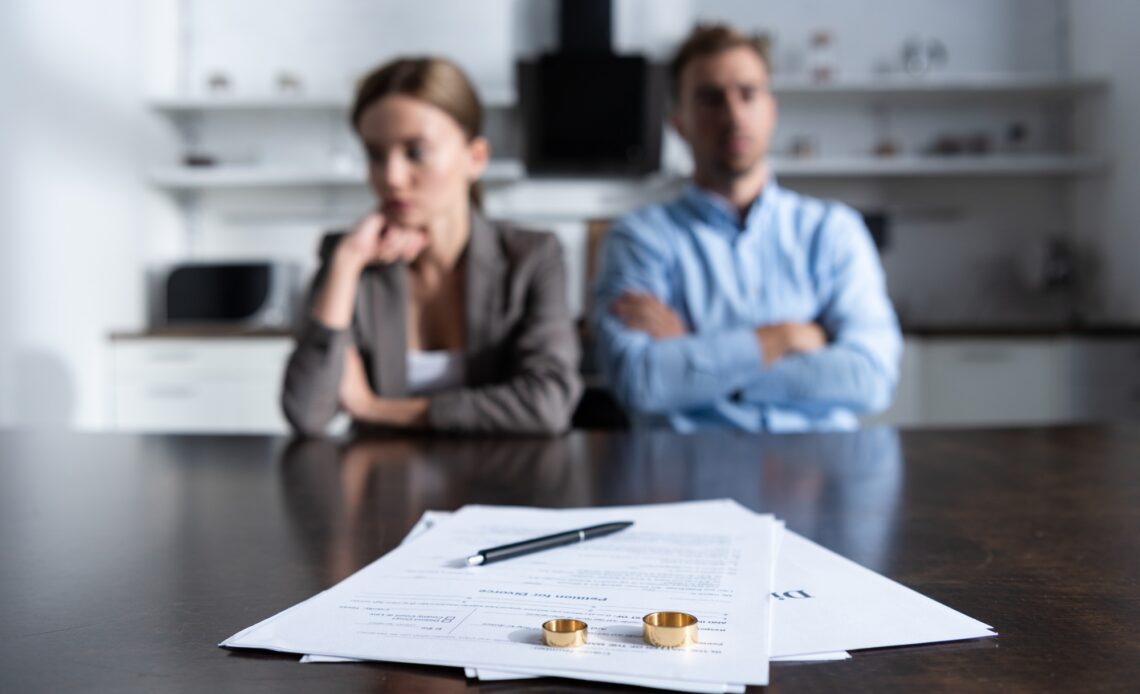 selective focus of couple sitting at table with divorce documents