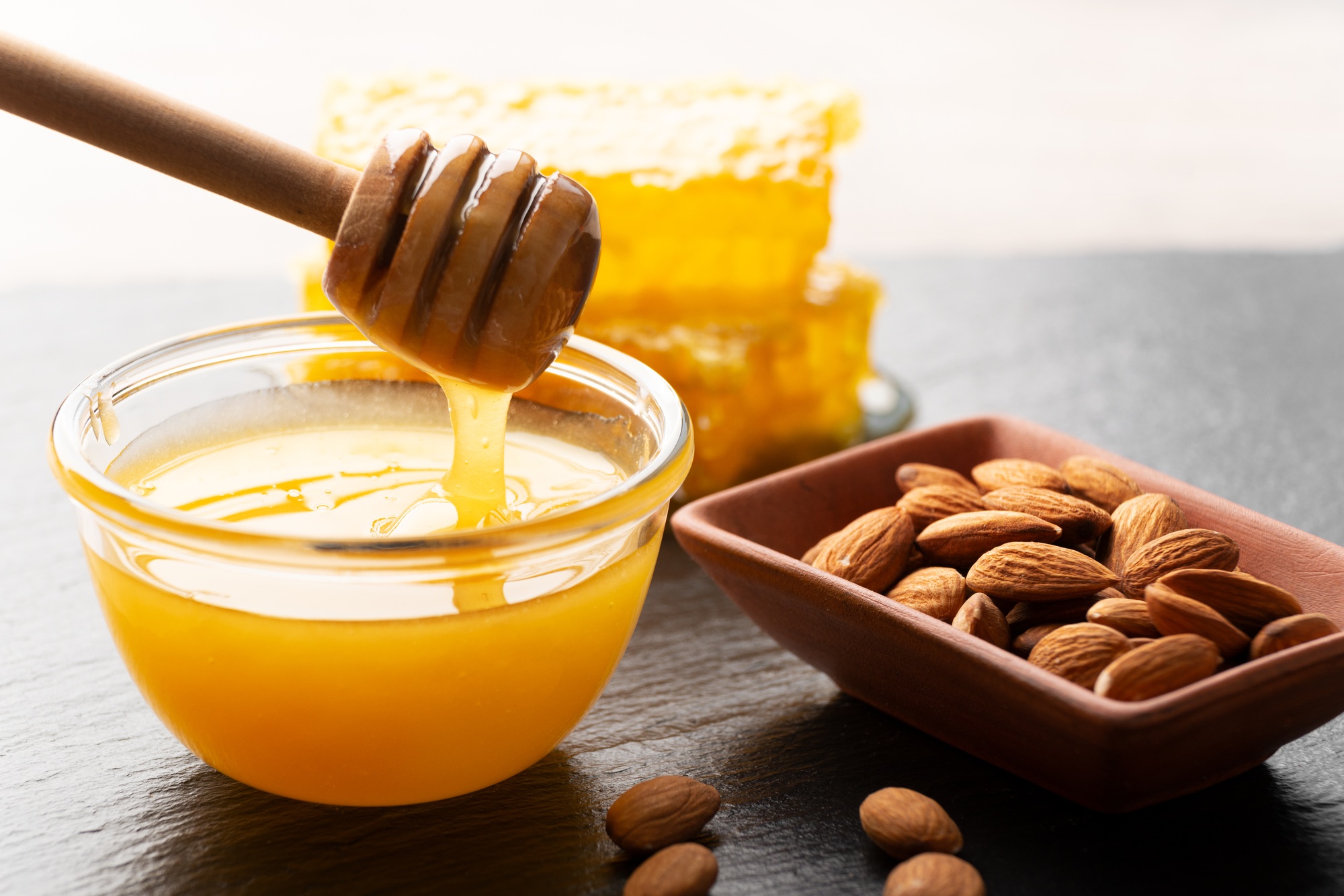 Slate tray with honey almonds and honeycomb on kitchen table